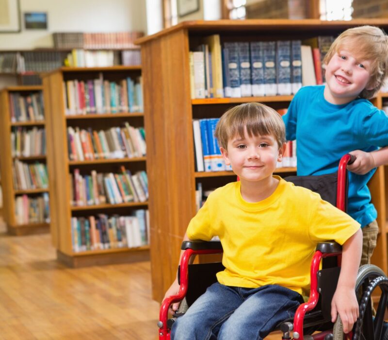 Cute pupils smiling at camera at the library at elementary school