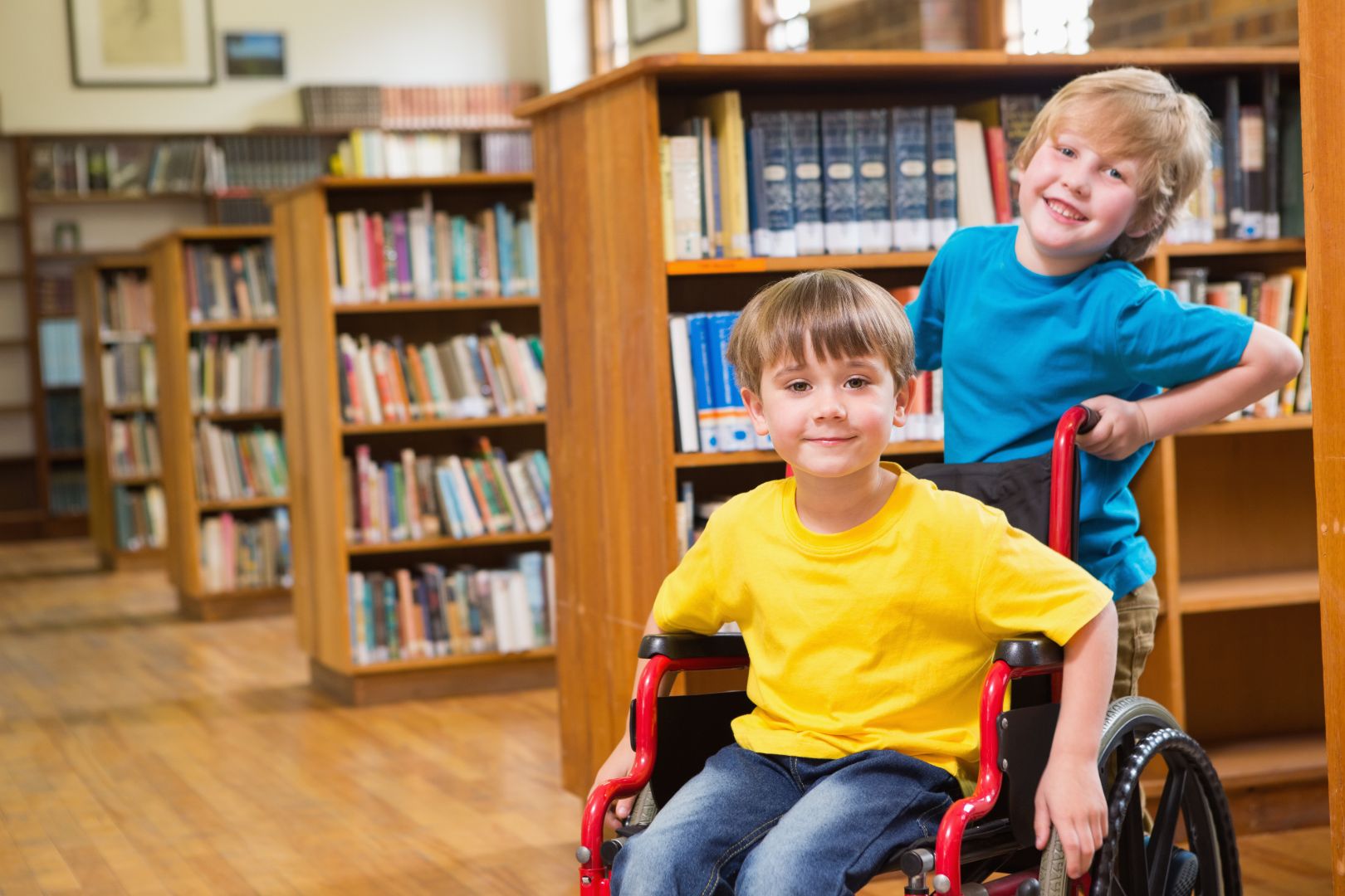 Cute pupils smiling at camera at the library at elementary school