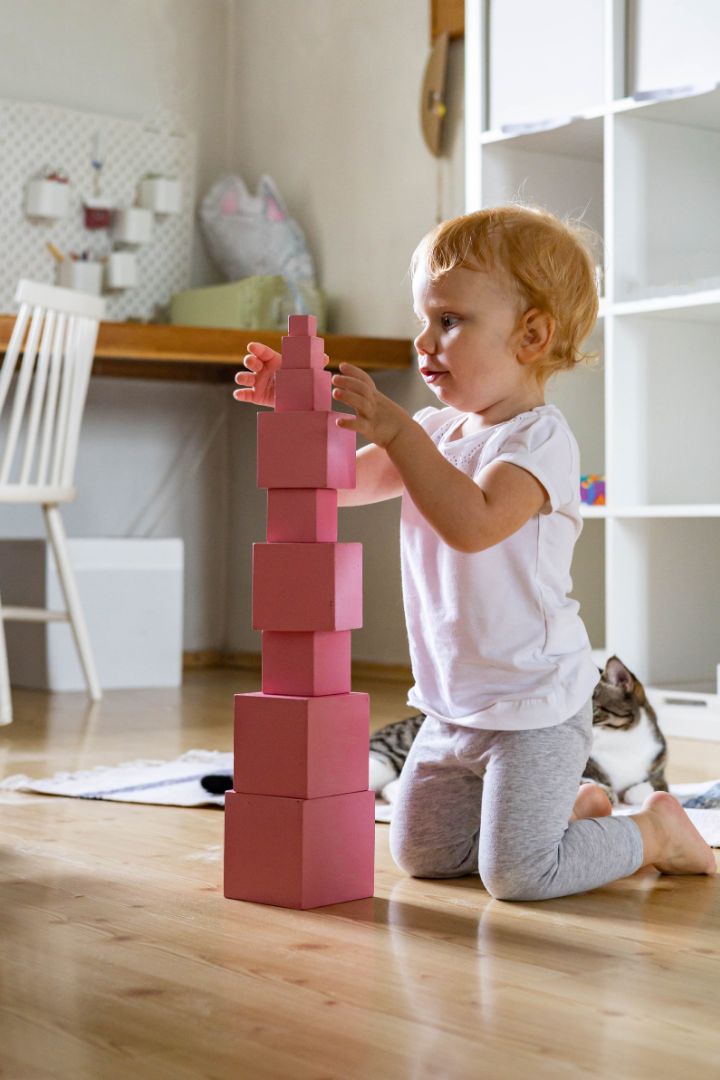 Cheerful toddler arrangement pink cubes assembling tower educational Maria Montessori materials